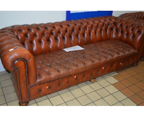 A TAN LEATHER THREE SEATER CHESTERFIELD SOFA, on cupped bun feet and casters, approximate size width 237cm x depth 89cm x hei