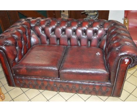 A BURGUNDY LEATHER CHESTERFIELD TWO SEATER SOFA