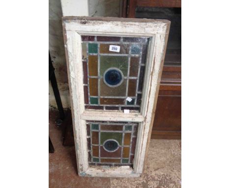 An antique white painted wood framed leaded window with two stained glass panels