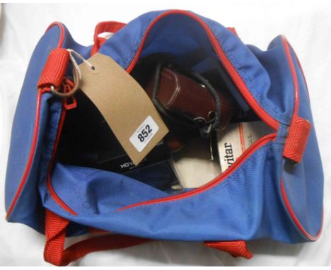 A canvas bag containing a vintage Cosina camera and other camera equipment