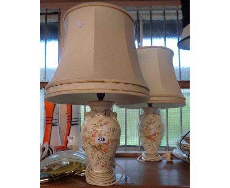 A pair of ceramic lamps with floral decoration on a cream ground