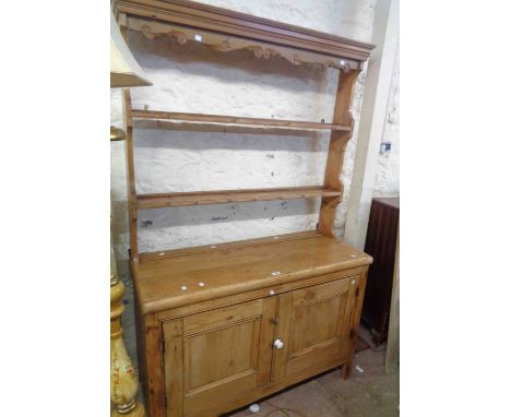 A 1.17m Victorian pine two part dresser with two shelf open plate rack and cup hooks, over a base with double panelled cupboa