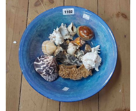 A ceramic bowl containing a quantity of shells and an onyx egg