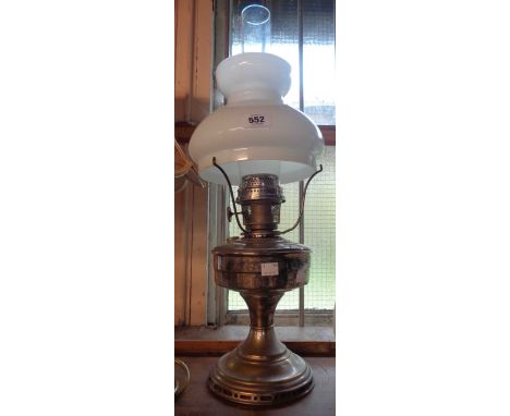 A vintage metal oil lamp with opaque glass shade