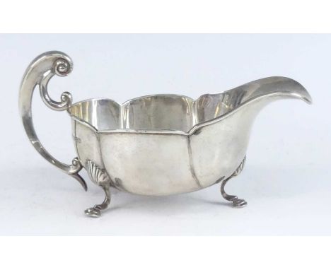 An Art Nouveau silver sauceboat, of lobed oval form, having a flying scroll handle, all upon three shell-capped hoof feet, ma