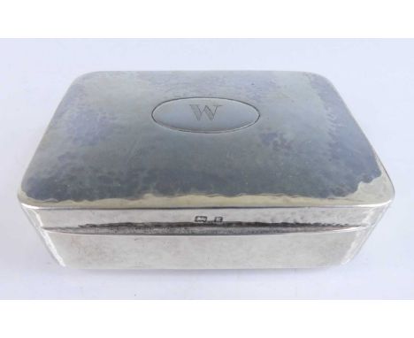 An Arts &amp; Crafts silver tobacco box, the hinged slightly domed cover engraved with a central W, having gilt-washed interi