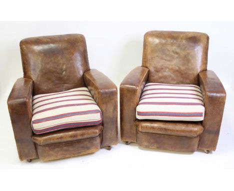 A pair of Art Deco tan leather and studded club armchairs, each with fabric striped upholstered squab cushioned seats, raised