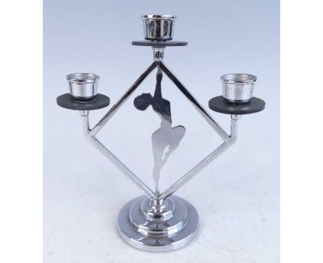 An Art Deco chrome three-branch candleholder, with central stylised female nude dancer on tiptoes within a lozenge shaped fra