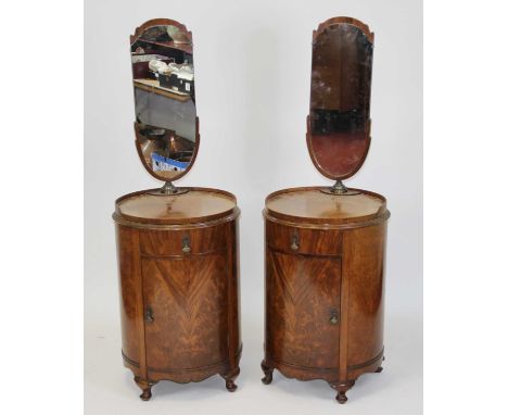 A pair of 1930s mahogany and flame mahogany cylindrical bedside cupboards, each with shaped swivel mirrors, further swivel to