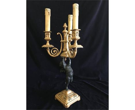 A metal lamp base cherub holding three tier candle light