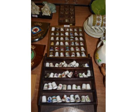 A collection of vintage and souvenir thimbles and wooden display cases.