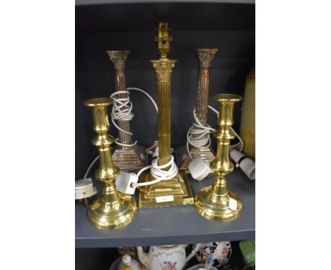 A selection of antique brass cast candle sticks or stems with Roman column design and similar converted brass bodied lamp