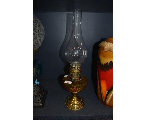 A brass bodied oil burning lamp with amber glass well made by Gladiator