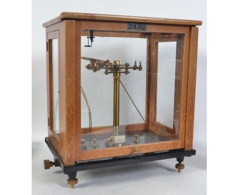 A pair of mid century wooden cased scientific scales in brass set to a black glass base with adjustable feet. The base marked
