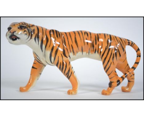 A Beswick ceramic figure of a prowling tiger, printed marks to underside of stomach, 21cms long. 22cms long