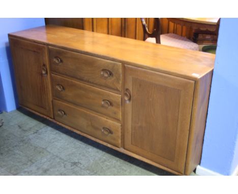 An Ercol Golden Dawn dresser base with three central drawers flanked by two cupboard doors.  155 cm wide