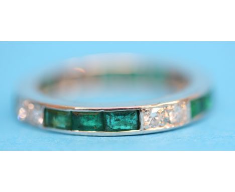 A platinum emerald and diamond eternity ring.