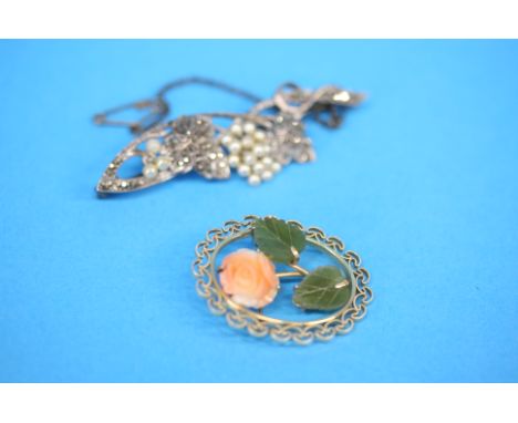 A gold coloured brooch set with carved coral rosehead and jade leaves and a 1920's marcasite and pearl set brooch. (2)