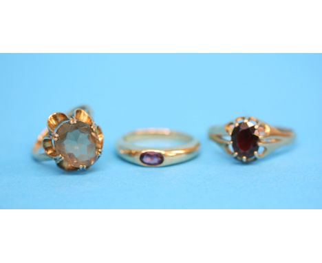 Three 9ct gold rings, one set with a garnet the other with a large citrine and a purple stone set ring.  Ring size W, L and N