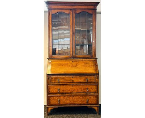 Antique oak dresser, the moulded cornice above two glazed doors opening to shelved interior, the base with drop front and thr