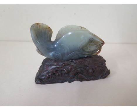 A Chinese 20th century jade carving of a fish on a well carved wooden stand, 8cm x 8cm, good condition 