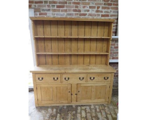 A 19th century stripped pine dresser with an open rack top above three drawers and two cupboard doors, with good light colour