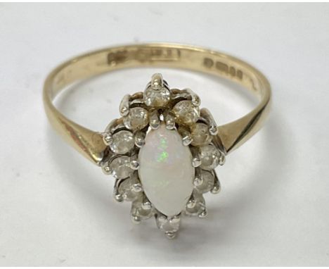 A 9ct gold ring set with an oval central opal and clear stones. The approximate ring size is between q and r.