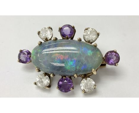 A 9ct gold brooch set with a large central opal and surrounded by alternating gemstones.