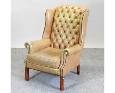 A tan leather upholstered button back armchair, on square legs