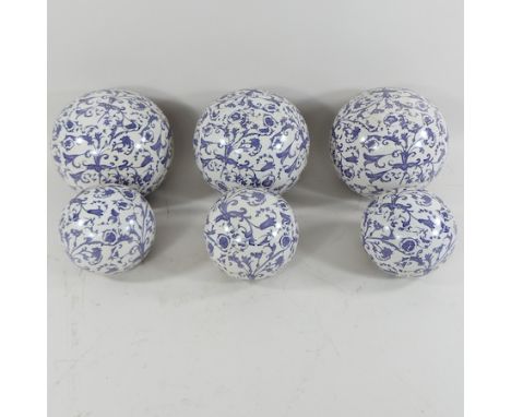 A set of six blue and white ceramic balls, largest 16cm