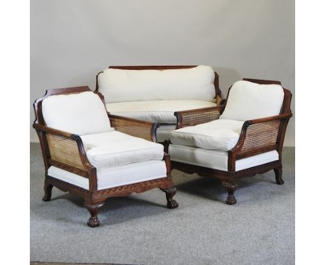 A 1920's carved walnut and  cream upholstered three piece bergere suite, on cabriole legs, comprising a sofa, 128cm, together