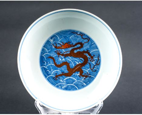 Chinese Art. A blue and white dish painted with a red dragon among waves and bearing a six character Qianlong seal mark at th