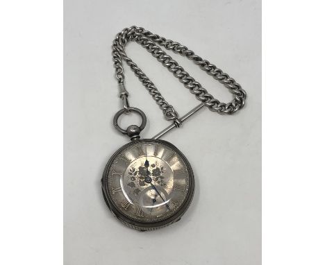 A large antique silver pocket watch with silver dial on heavy antique silver Albert chain