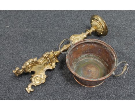 An antique twin-handled brass pan and an ornate brass candlestick 