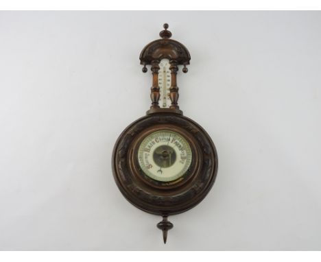 An early 20th century aneroid barometer, incorporating a thermometer in a carved walnut case, H. 47cm.