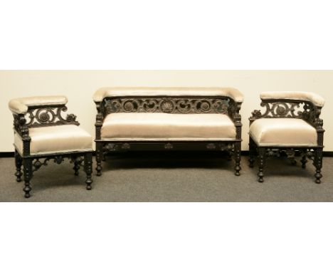 A Neoclassical ebonized sofa, richly carved, and two ditto corner chairs, H 67 - W 51 - 124 - D 51 - 59 cm