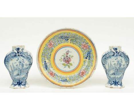 A 19thC polychrome decorated Flemish earthenware plate; added two blue and white decorated Dutch Delftware vases and covers, 