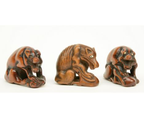 Three Japanese wooden katabori netsuke depicting wolves defending their prey, early Meiji-period, two of them signed, W 4,8 -