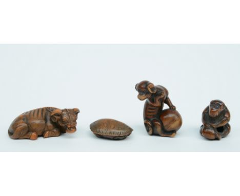 Three Japanese wooden katabori netsuke, one depicting a buffalo at rest, one a monkey playing with a peach kernel and one a l
