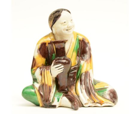 A Chinese Sansai sculpture depicting a seated figure holding a vase, Kangxi, 18thC