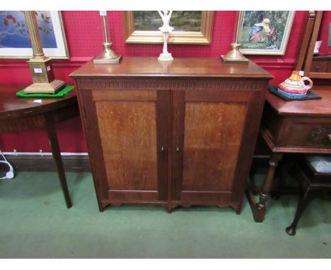 In the manner of 'Heals' an oak two door cupboard with multiple shelf interior the chip carved frieze over a shaped apron, 91