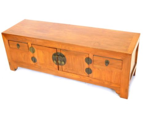 An oriental hardwood low cabinet, with two central panelled doors, each with circular handles and escutcheons, flanked by two