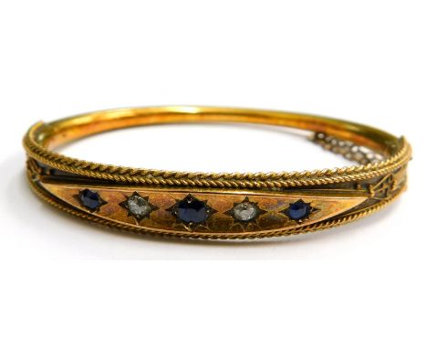 A Victorian 15ct gold hinged bangle, with a diamond shaped top section set, with sapphires and diamonds, with reeded filigree