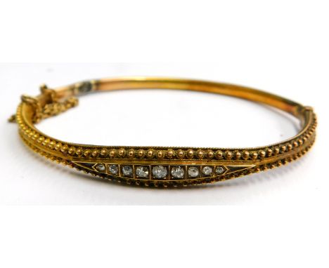 A Victorian hinged bangle, the half hoop design with reeded filigree type decoration, with central diamond set panel, with sa