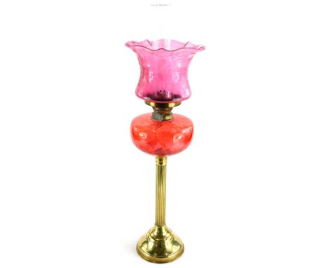 A brass oil lamp, with pink coloured reservoir and cranberry tinted shade, with etched decoration in Art Nouveau style. 