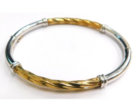 A 9ct gold hinged bangle, of two colour design, with silvered and yellow gold finish, the central panel of twist design, on h