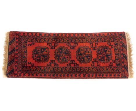 An Afghan narrow rug or runner, with a design of four medallions on an orange ground, with multiple borders, 135cm x 50cm.
