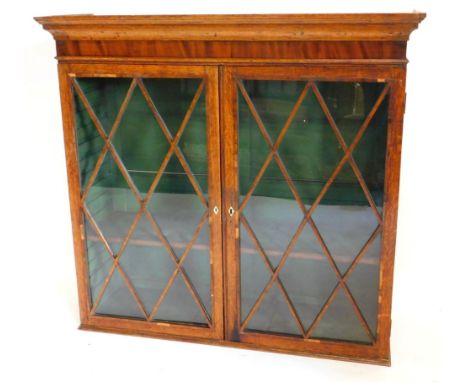 An early 19thC oak and mahogany crossbanded bookcase, with a moulded cornice above two astragal glazed doors, enclosing a sin