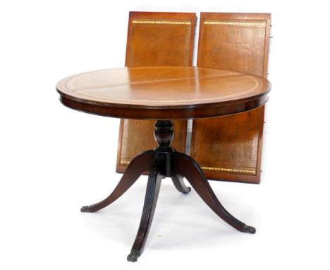 A mahogany extending dining table, the circular top with a brown tool leather insert, on turned column and reeded splayed leg