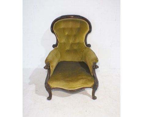 A Victorian Grandfather chair with button-back detailing, raised on cabriole legs with carved decoration.